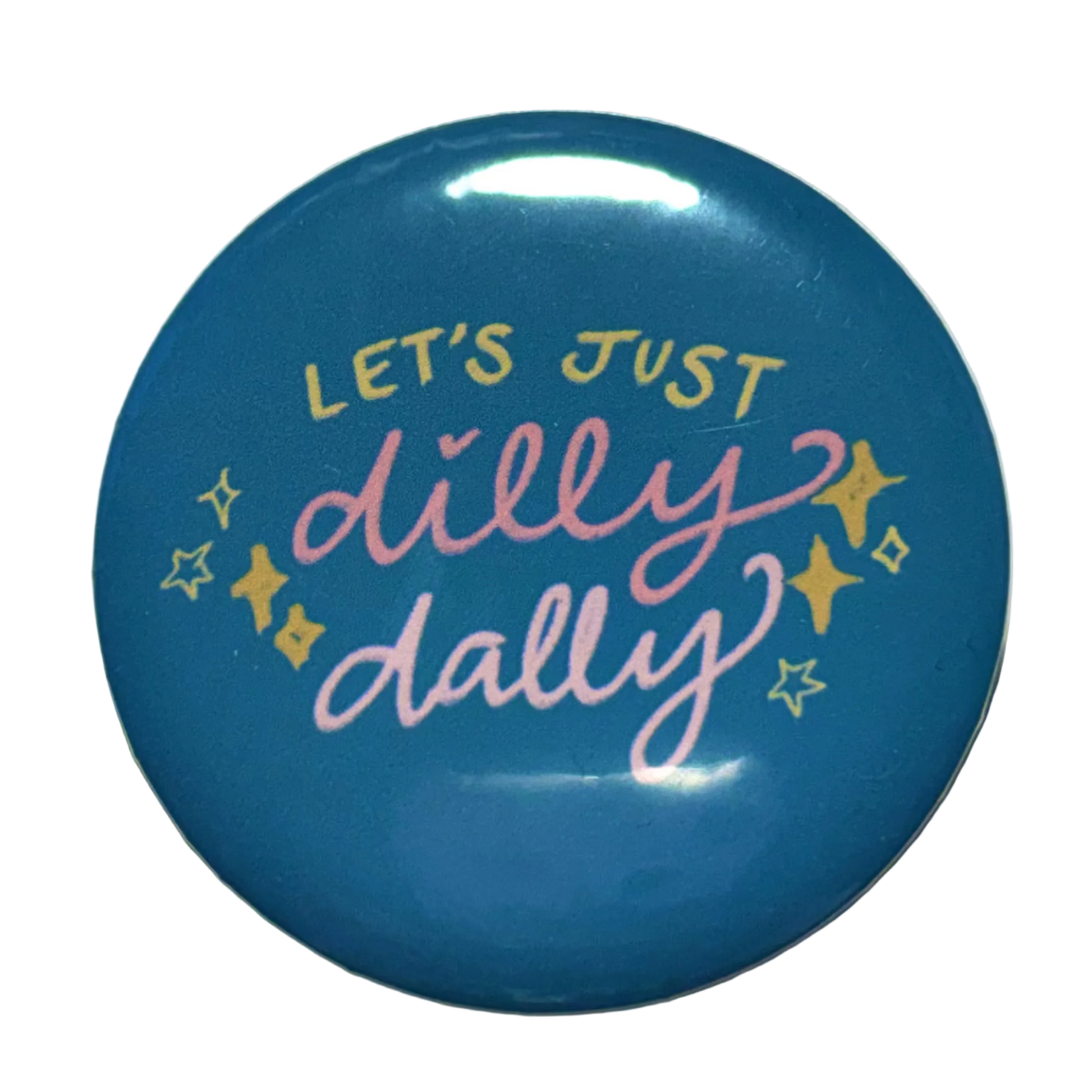 A round blue button badge with the phrase 'LET'S JUST dilly dally' in pink and yellow lettering, accented with small yellow stars, on a light beige background.
