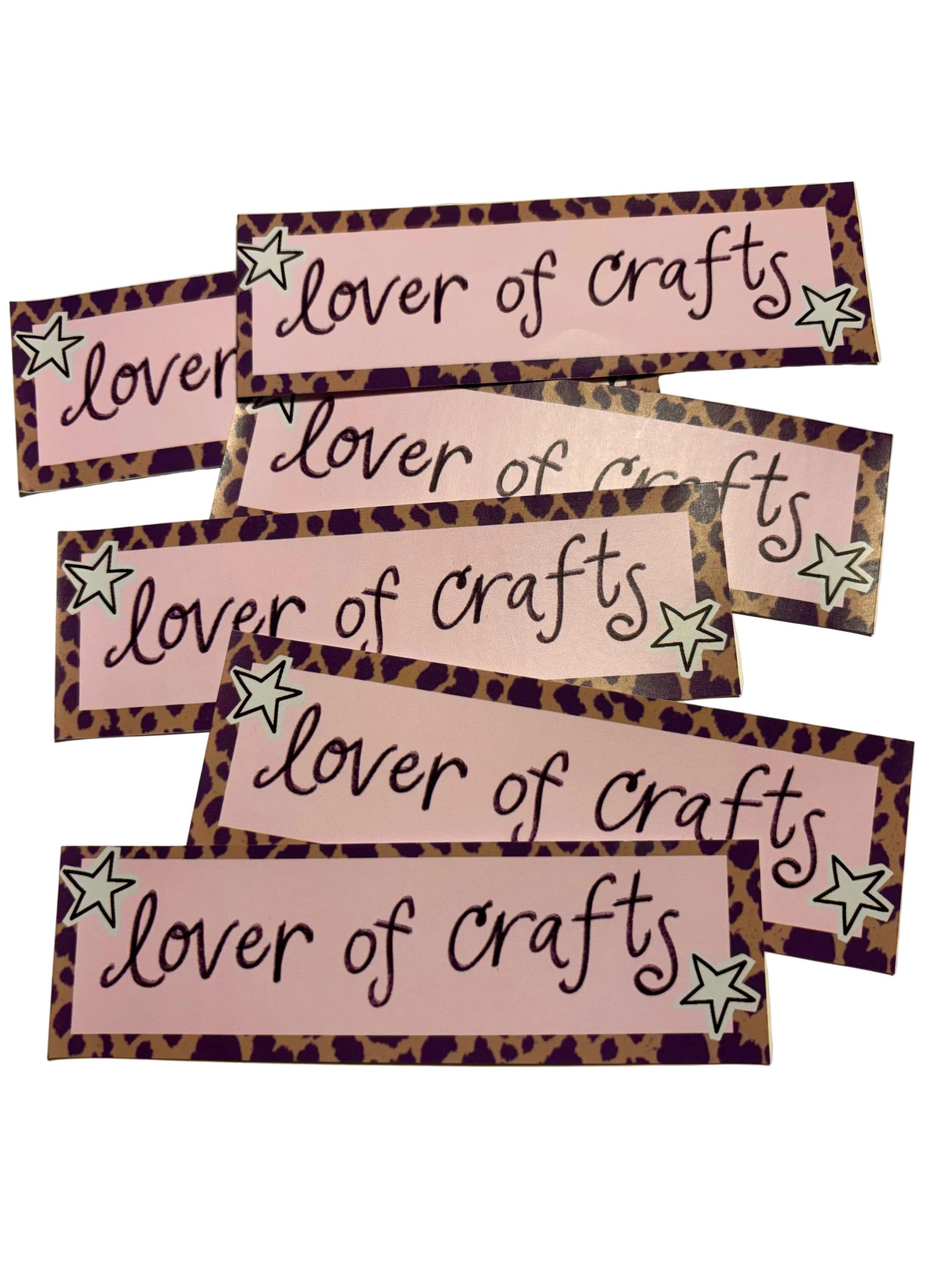 Five rectangular craft labels with the phrase 'lover of crafts' in black script on a pink background, each bordered in a leopard print pattern with two small star accents